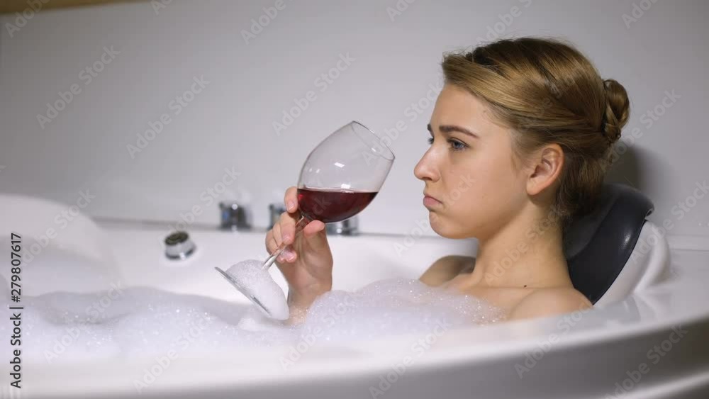 Depressed girl lying in bath with foam bubbles drinking wine, boyfriend break up Depressed girl lying in bath with foam bubbles drinking wine, boyfriend break up