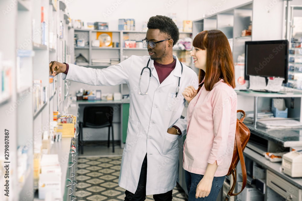 Obraz premium Experienced African American man pharmacist consulting female customer in modern pharmacy