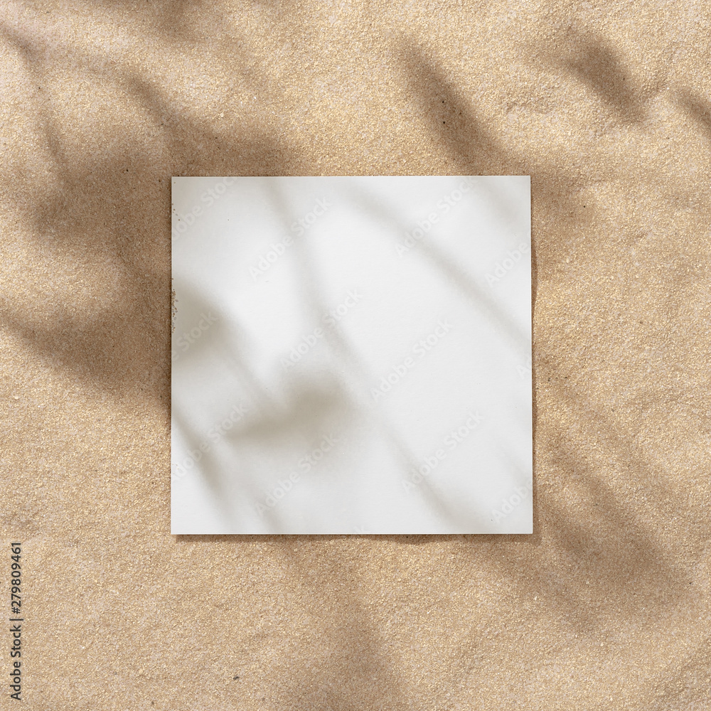Fototapeta premium Summer beach day scene with tropical palms shadow on sand background with paper frame copy space. Minimal sunlight tropical flat lay arrangement.