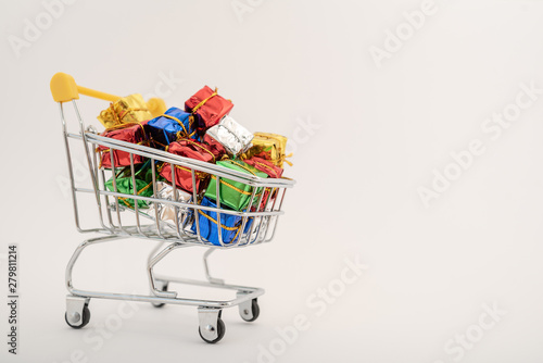 Christmas gifts in a supermarket trolley on white background. Online shopping concept - trolley full of gifts. Black Friday and Cyber Monday © Pavel