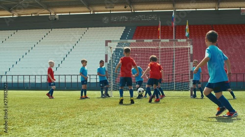 Small boy in professional soccer uniform kicking ball through defensive wall on training