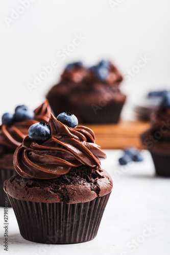 Chocolate cupcakes with blueberries on white table, close up