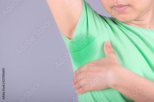 Close-up young women with hyperhidrosis sweating. Young woman with sweat stain on her clothes against grey background. Healthcare concept.