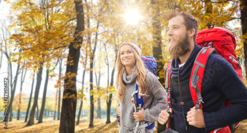adventure  travel  tourism  hike and people concept - couple of travelers with backpacks over autumn park background