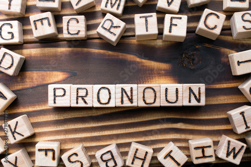 word pronoun composed of wooden cubes with letters, Part of speech concept scattered around the cubes random letters, top view on wooden background