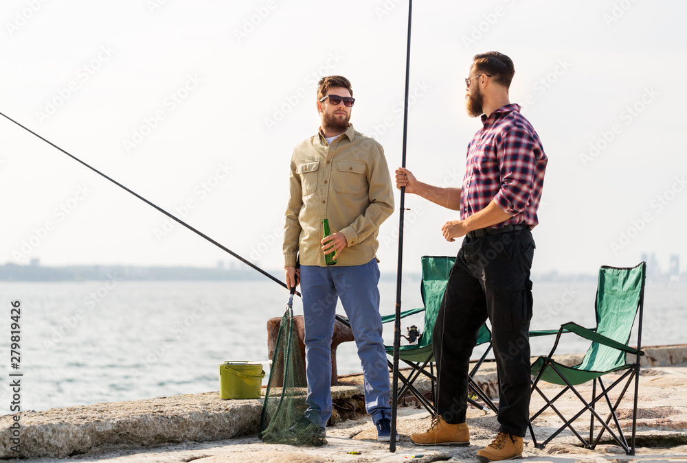 leisure and people concept - male friends with fishing rods and beer on pier at sea leisure and people concept - male friends with fishing rods and beer on pier at sea