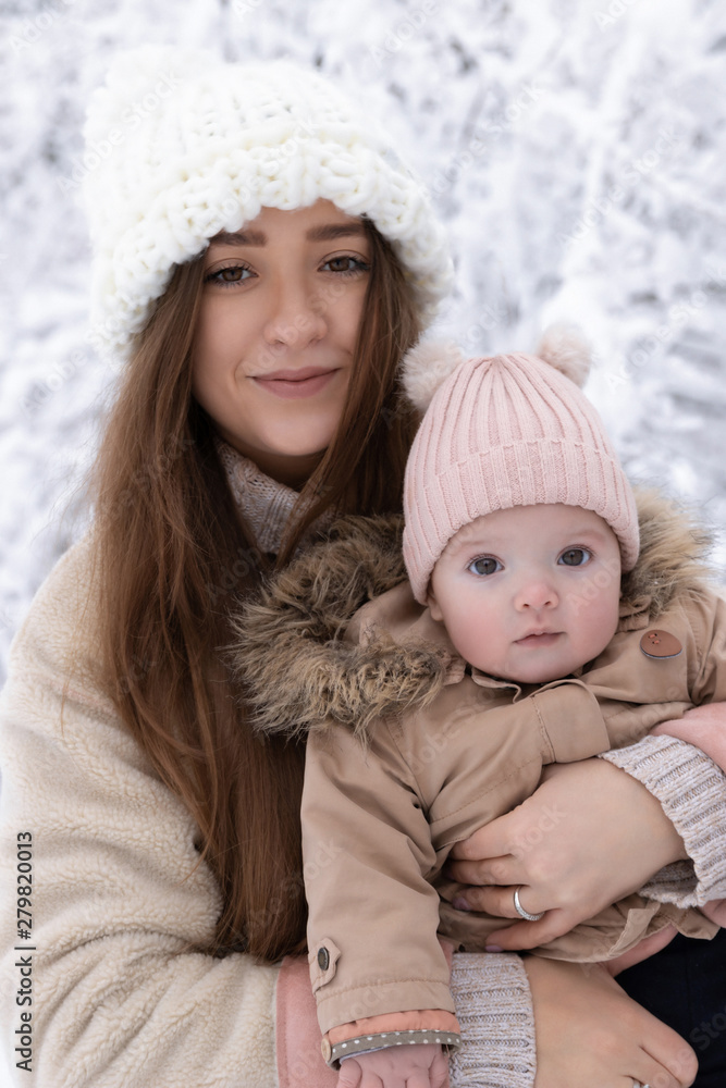 A young mother with a small child plays in the snow, they are having fun and enjoying the snowfall. Winter walk outside.