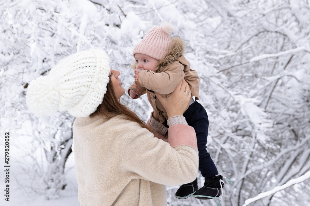 A young mother with a small child plays in the snow, they are having fun and enjoying the snowfall. Winter walk outside. A young mother with a small child plays in the snow, they are having fun and enjoying the snowfall. Winter walk outside.