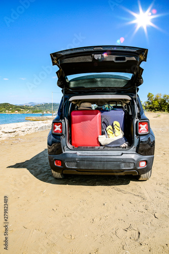 Black summer car on the sunny sandy beach. Blue clear sunshine sky view in distance.  © magdal3na