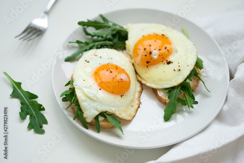 Sandwiches with ricotta cheese  arugula and fried egg on white wooden background. Selective focus. Healthy food concept