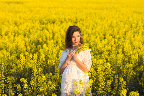 Pregnant girl with flowers in her hands. Belly of a pregnant woman. The concept of pregnancy. Blurred background over green nature. Pregnant tummy close up. spring park holding a bouquet. © SYARGEENKA