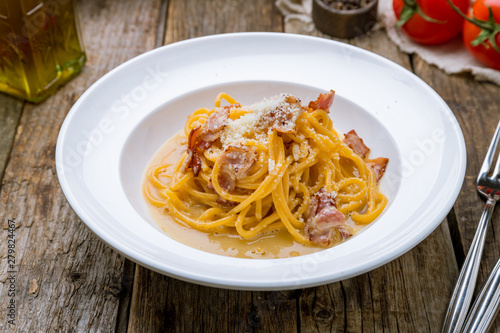 Spaghetti Carbonara with bacon and parmesan on wooden table