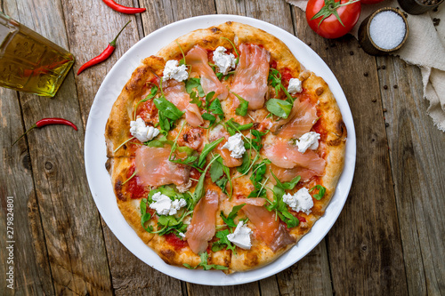 Pizza with salmon and Philadelphia cheese and aragula on wooden table