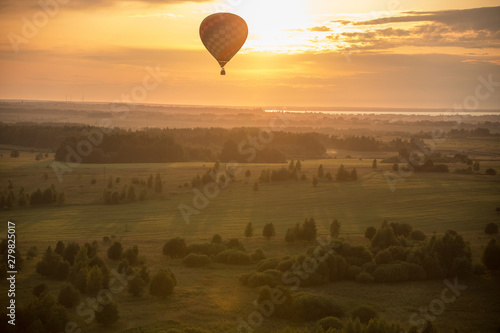 A colorful air balloon flying over the field - bright yellow sunset © KONSTANTIN SHISHKIN