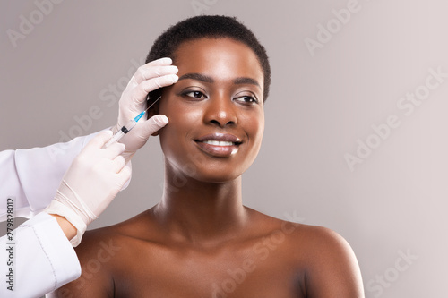Young black woman getting beauty injection under skin photo