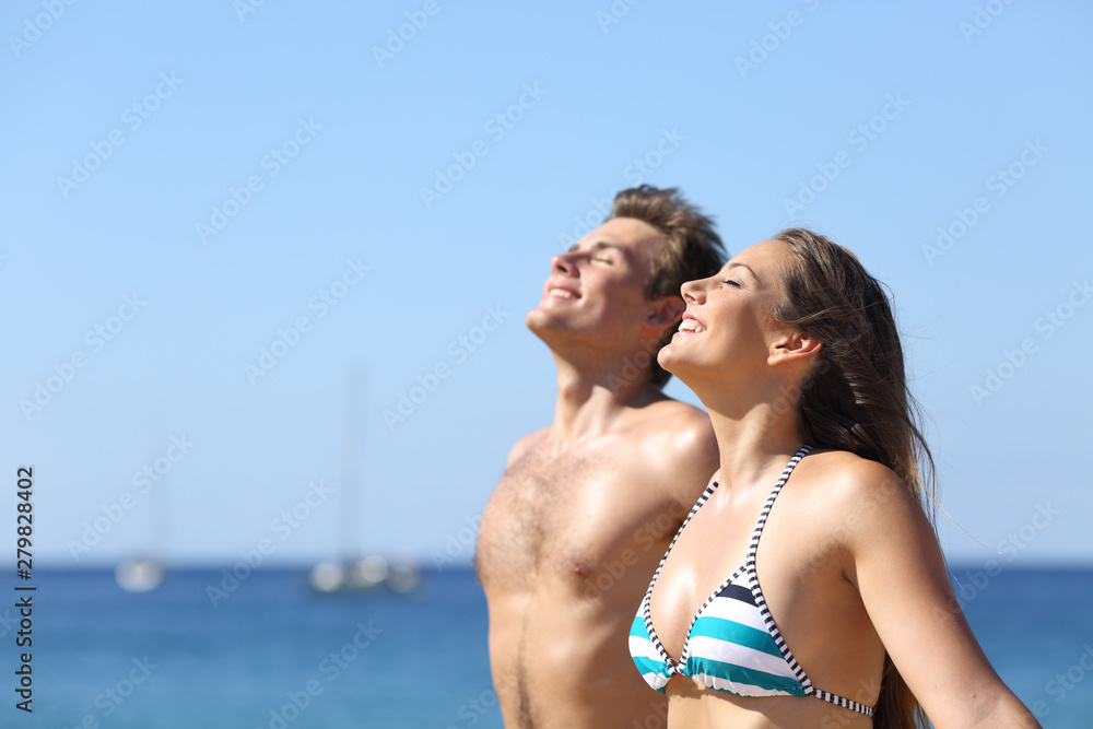 Happy couple of tourists breathing deep on the beach Happy couple of tourists breathing deep on the beach