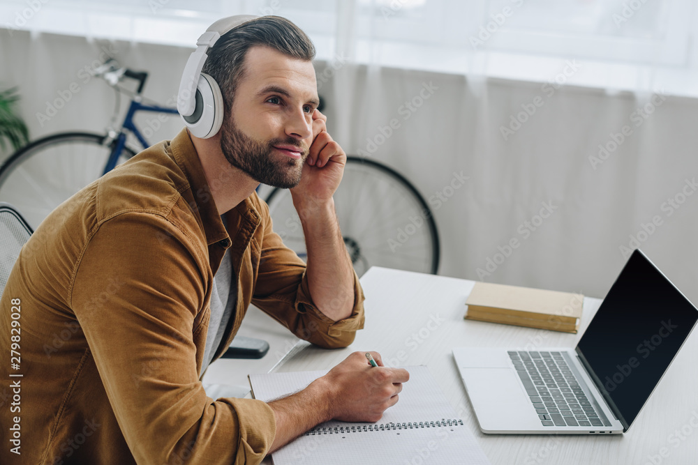 Fototapeta premium good-looking man listening music, holding pencil and looking away