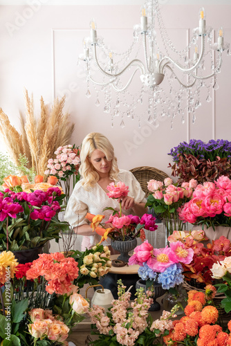 Beautiful blonde florist woman picks up flowers and creates wonderful bouquet