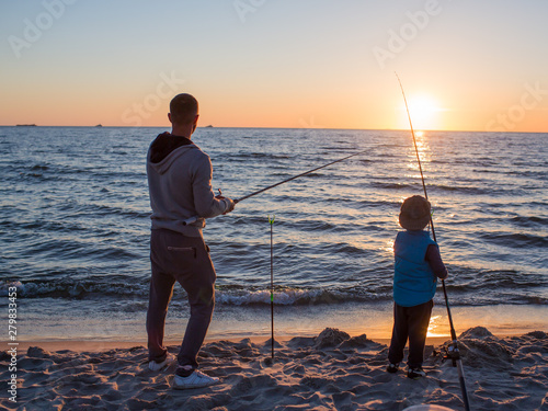 Obraz na płótnie Father and son fishing on the beach of Baltic Sea in the sunset time. w salonie