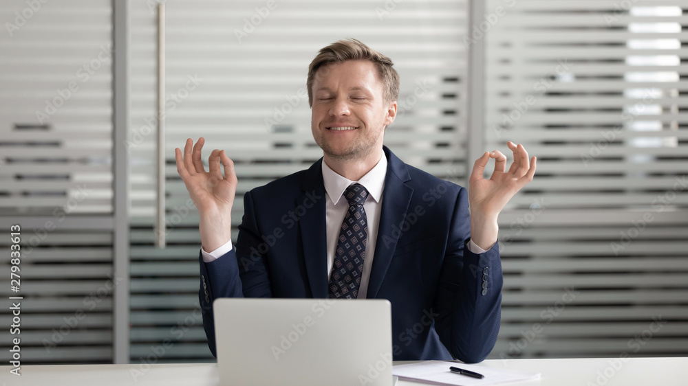 Mindful happy businessman relaxing meditating sit at office desk Mindful happy businessman relaxing meditating sit at office desk