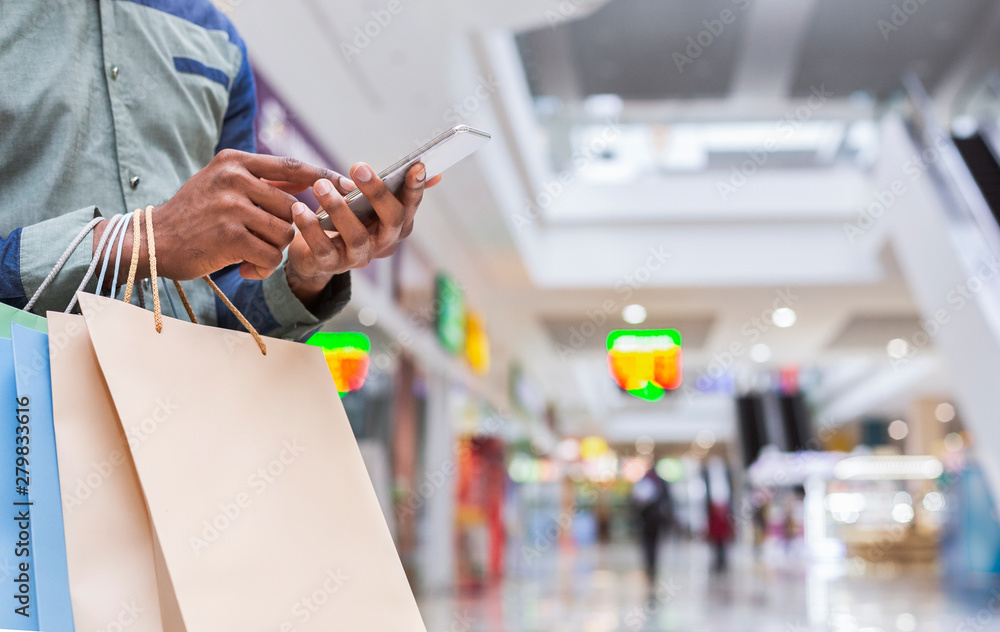 Unrecognizable african american guy with cellphone in mall