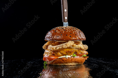 Gourmet craft bacon cheeseburger with tomatoes and onion rings.