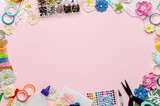 Paper flowers, scissors, paper and scrapbooking items on pink background. Scrapbooking, top view, empty space for text in the center