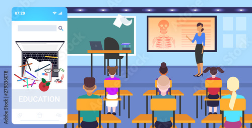 pupils sitting desks looking at female teacher pointing skeleton biology anatomy lesson school education concept online mobile app modern classroom interior full length horizontal