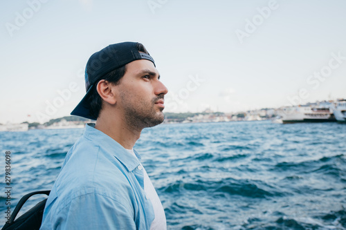 Portrait of a young man against the background of the sea and the city.