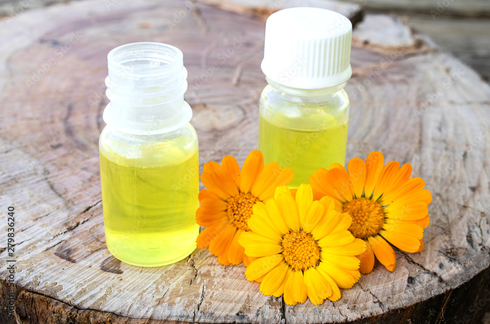 Bottle of calendula oil on a wooden background. Extract of tincture of calendula. Bottle of calendula oil on a wooden background. Extract of tincture of calendula.
