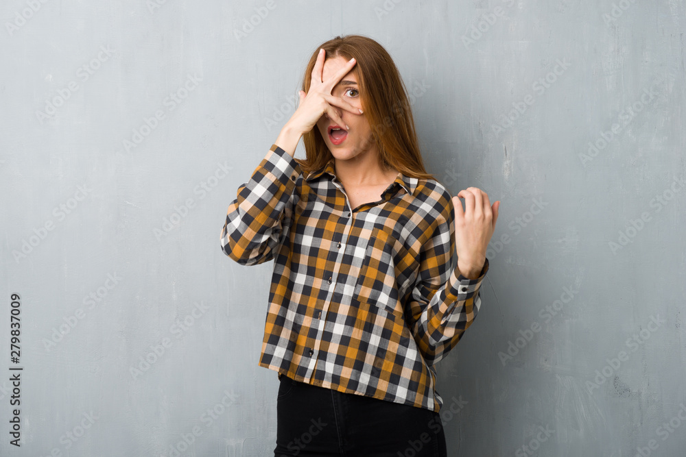 Young redhead girl over grunge wall with surprise and shocked facial expression Young redhead girl over grunge wall with surprise and shocked facial expression