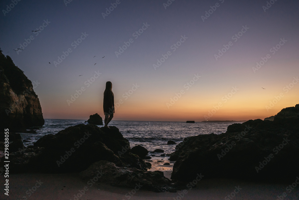 Young woman silhouetted against an orange sunset