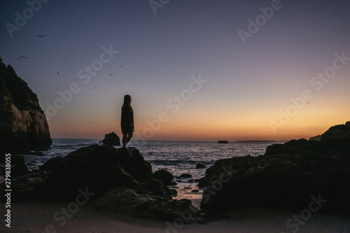 Young woman silhouetted against an orange sunset