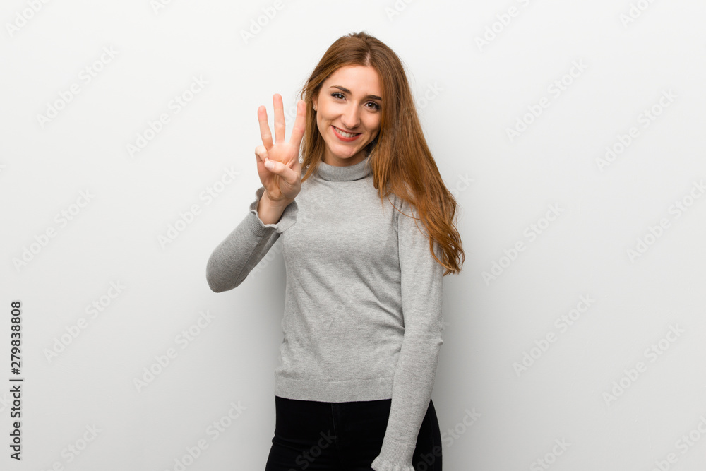 Redhead girl over white wall happy and counting three with fingers Redhead girl over white wall happy and counting three with fingers