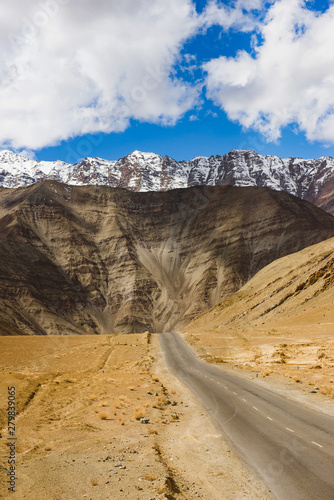 Empty road leading towards a snow capped mountain in leh, ladakh, india. A gravity hill where slow speed cars are drawn against gravity is famously known as "Magnetic Hill" , a natural wonder.