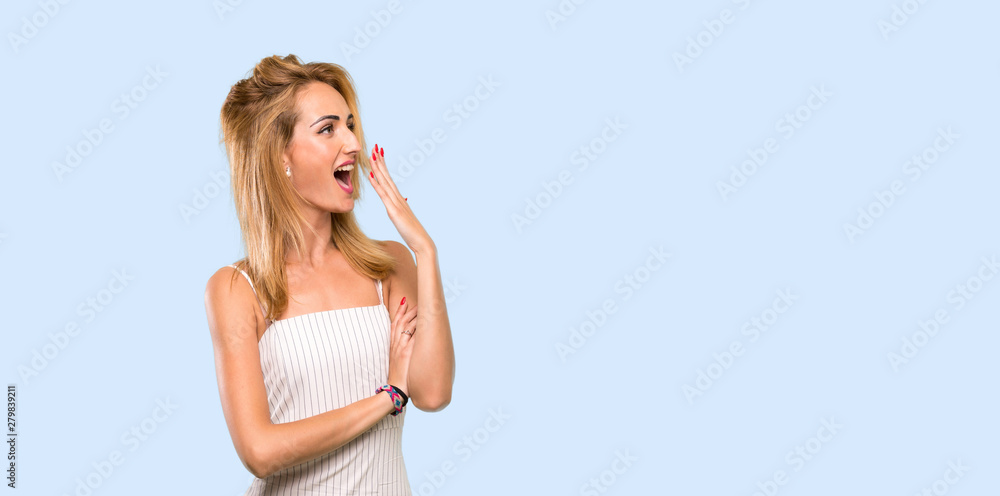 Young blonde woman yawning and covering wide open mouth with hand over isolated blue background Young blonde woman yawning and covering wide open mouth with hand over isolated blue background