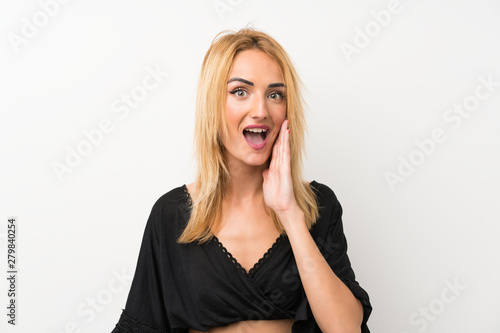 Young blonde woman over isolated white wall with surprise and shocked facial expression