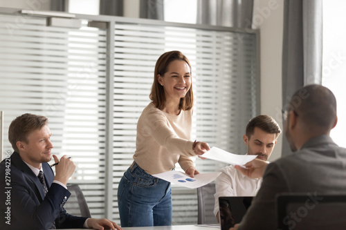 Happy female boss giving paper financial report to employees clients photo