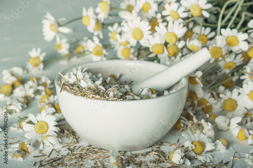 Rural still-life - chamomile crushed in a mortar on the background of a bouquet of daisies  closeup
