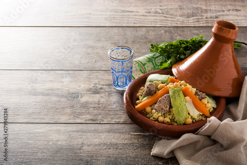 Traditional tajine with vegetables, chickpeas, meat and couscous on wooden table. Copyspace photo