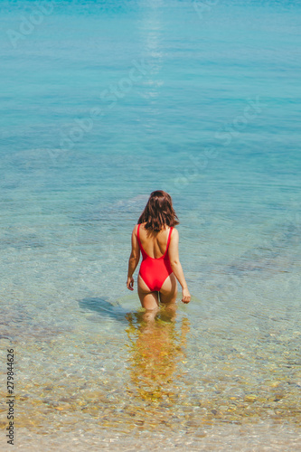 woman standing in sea in the middle in red swimming suit. view from behind. sexy ass
