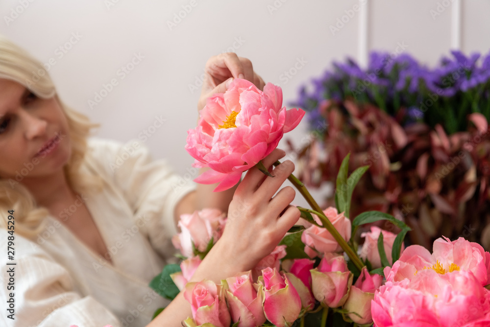 Fototapeta premium Hands of a beautiful young florist woman making modern bouquet of different flowers