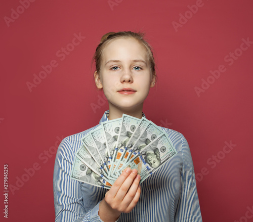 Pretty happy teen girl and money us dollars on pink background photo