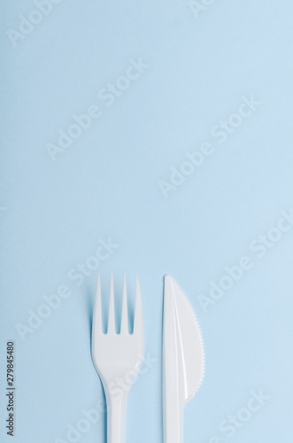 Plastic white disposable fork and knife on a blue ba