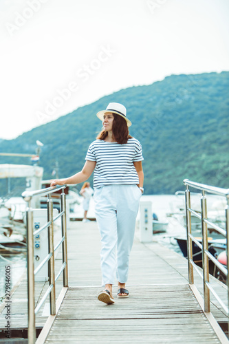 woman in white fashion luxury view walking by dock boats on background © phpetrunina14