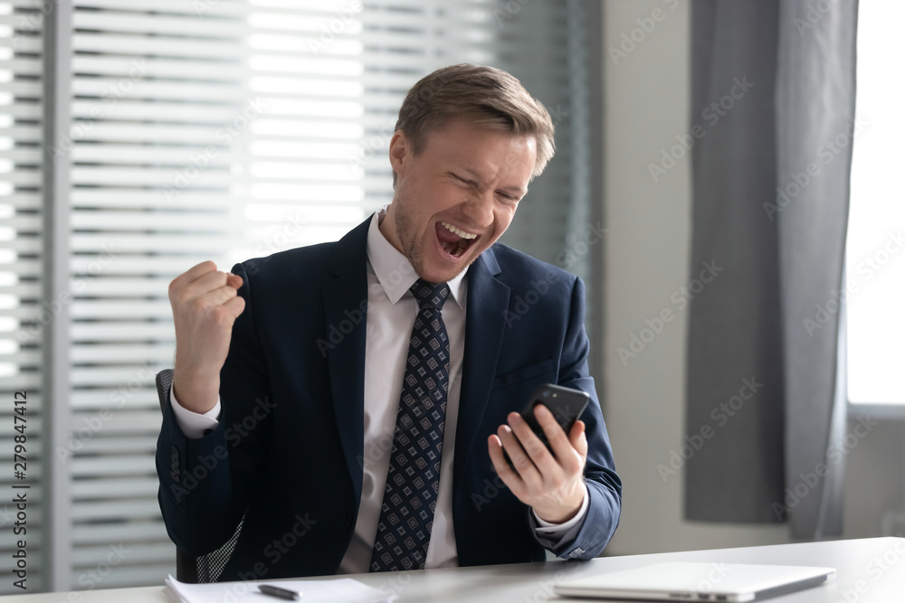 Euphoric happy businessman wear suit celebrate mobile win Euphoric happy businessman wear suit celebrate mobile win