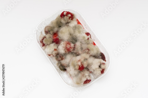 Canvas Print Closeup of rotten moldy raspberry in plastic box isolated on white
