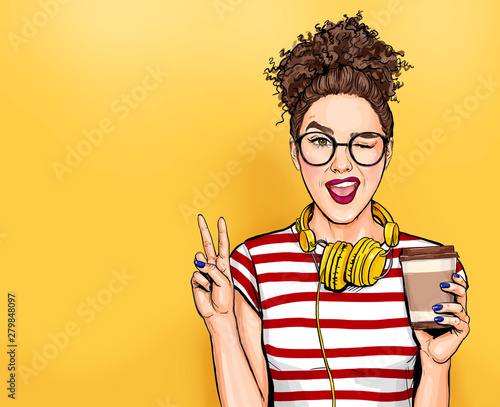 Mrugająca kobieta w okularach z telefonami na głowie robi gest pokoju Dziewczyna pop-artu, trzymając kubek kawy.