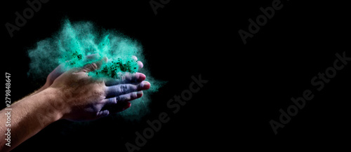 Colored holi powder in woman hands on black background