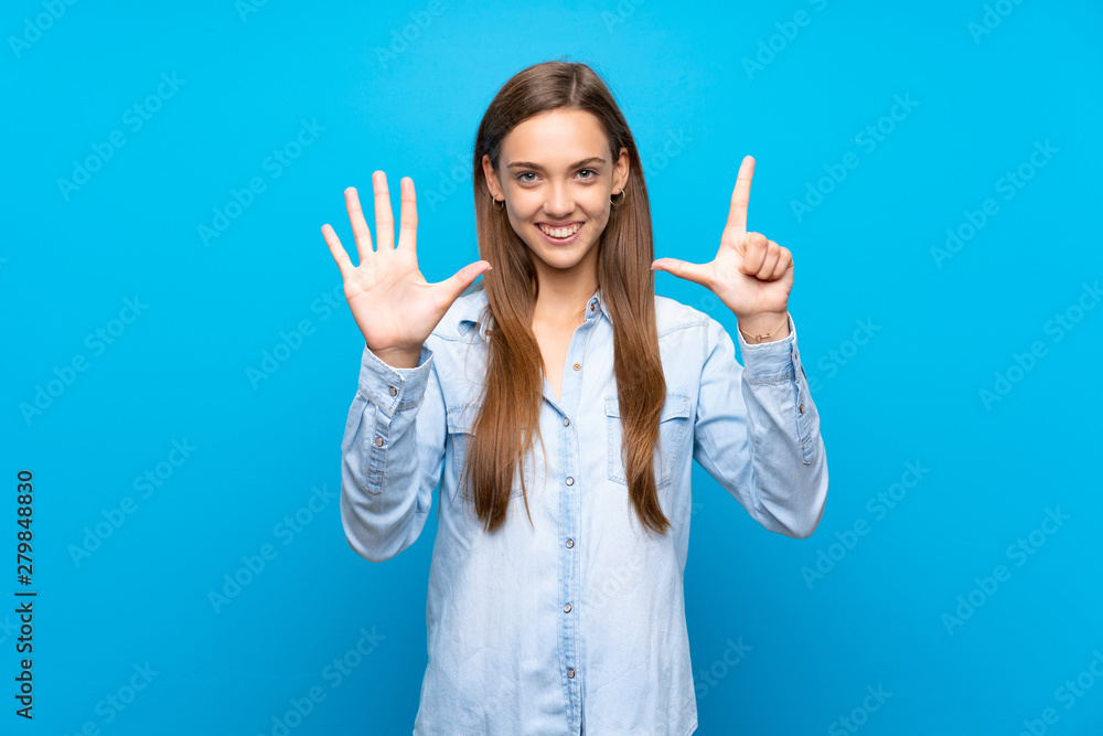 Young woman over isolated blue background counting seven with fingers